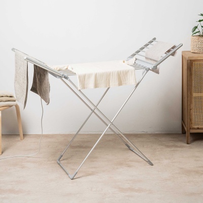 Estendal de roupa em metal com toalhas em tons creme e castanho num ambiente interior