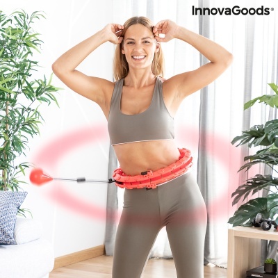Mulher a usar aro de fitness vermelho em roupa desportiva cinzenta no interior com logo InnovaGoods.
