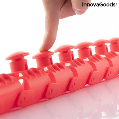 Massageador de mãos vermelho com botões e mão a pressionar um botão