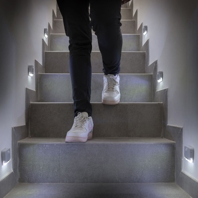 Escada interna com iluminação e pessoa a descer com sapatilhas brancas