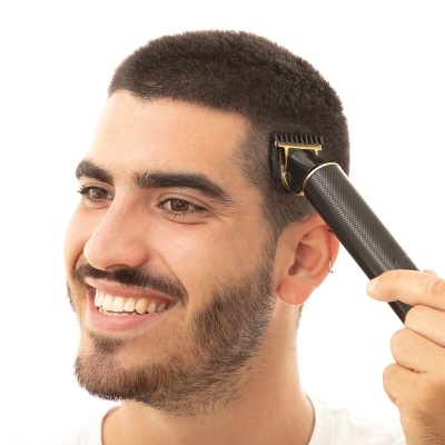Homem a usar máquina de cortar cabelo preta com detalhe dourado