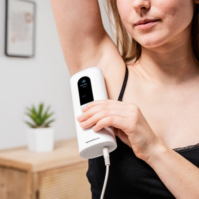 Dispositivo branco com ecrã preto usado sob a axila de mulher em ambiente interior