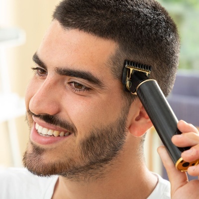 Homem a cortar cabelo com aparador preto e dourado