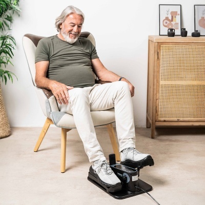 Homem sentado numa poltrona com máquina de exercício para os pés