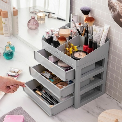 Organizador cinza para maquilhagem com produtos e pincéis numa bancada branca