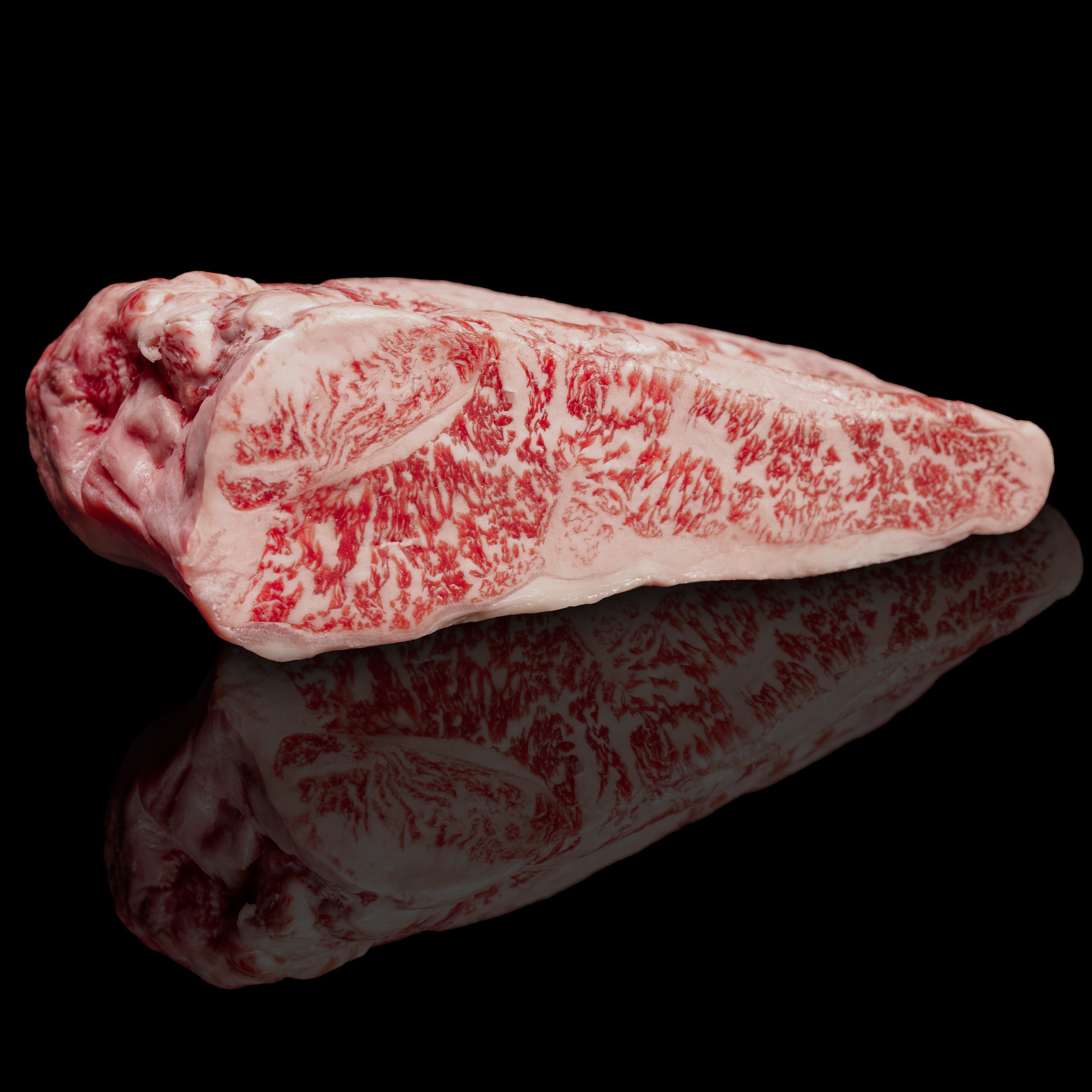 Wagyu do Japão Pedaço de carne cru marmorizada sobre superfície preta refletora