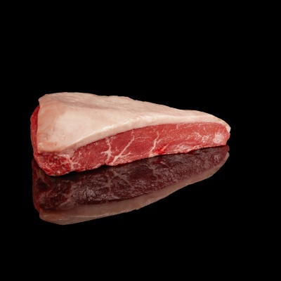 Pedaço cru de carne vermelha com gordura numa superfície preta refletora