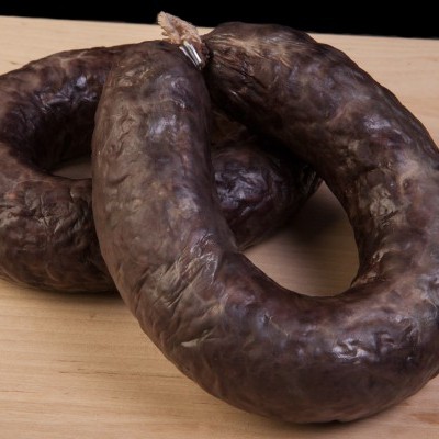 Morcelas escuras com textura enrugada numa tábua de madeira clara