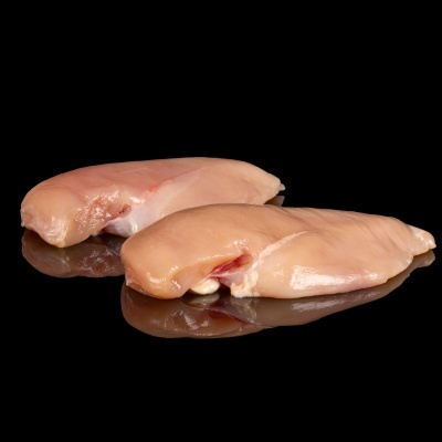 Dois peitos de frango crus sobre superfície preta brilhante