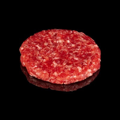 Hambúrguer cru de carne moída vermelha redondo sobre superfície preta