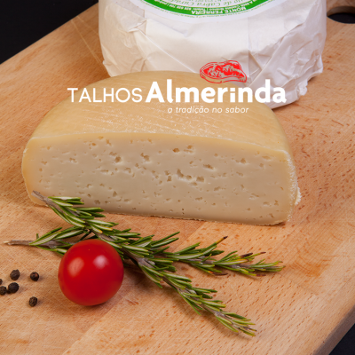 Queijo semi-curado em cunha sobre tábua com alecrim, tomate-cereja e pimenta, embalagem branca ao fundo