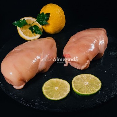 Peito de frango cru com limão e lima num prato preto