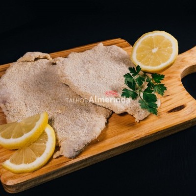 Bife cru com limão e salsa numa tábua de madeira sobre fundo preto