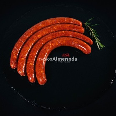 Cinco salsichas cruas em prato preto com alecrim