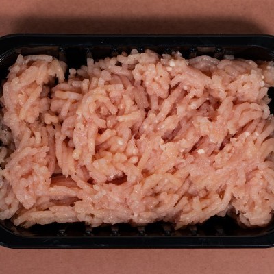 Embalagem preta com carne picada fresca rosada em fundo castanho