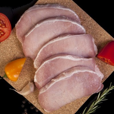 Fatias de fiambre sobre tábua de cortiça com tomate, pimentos, alho, pimenta e alecrim