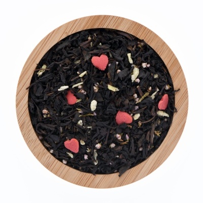 taça redonda de madeira com mistura de chá preto e corações vermelhos de confeitos