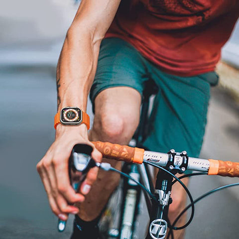 Relógio digital com bracelete laranja num ciclista a segurar o guiador da bicicleta
