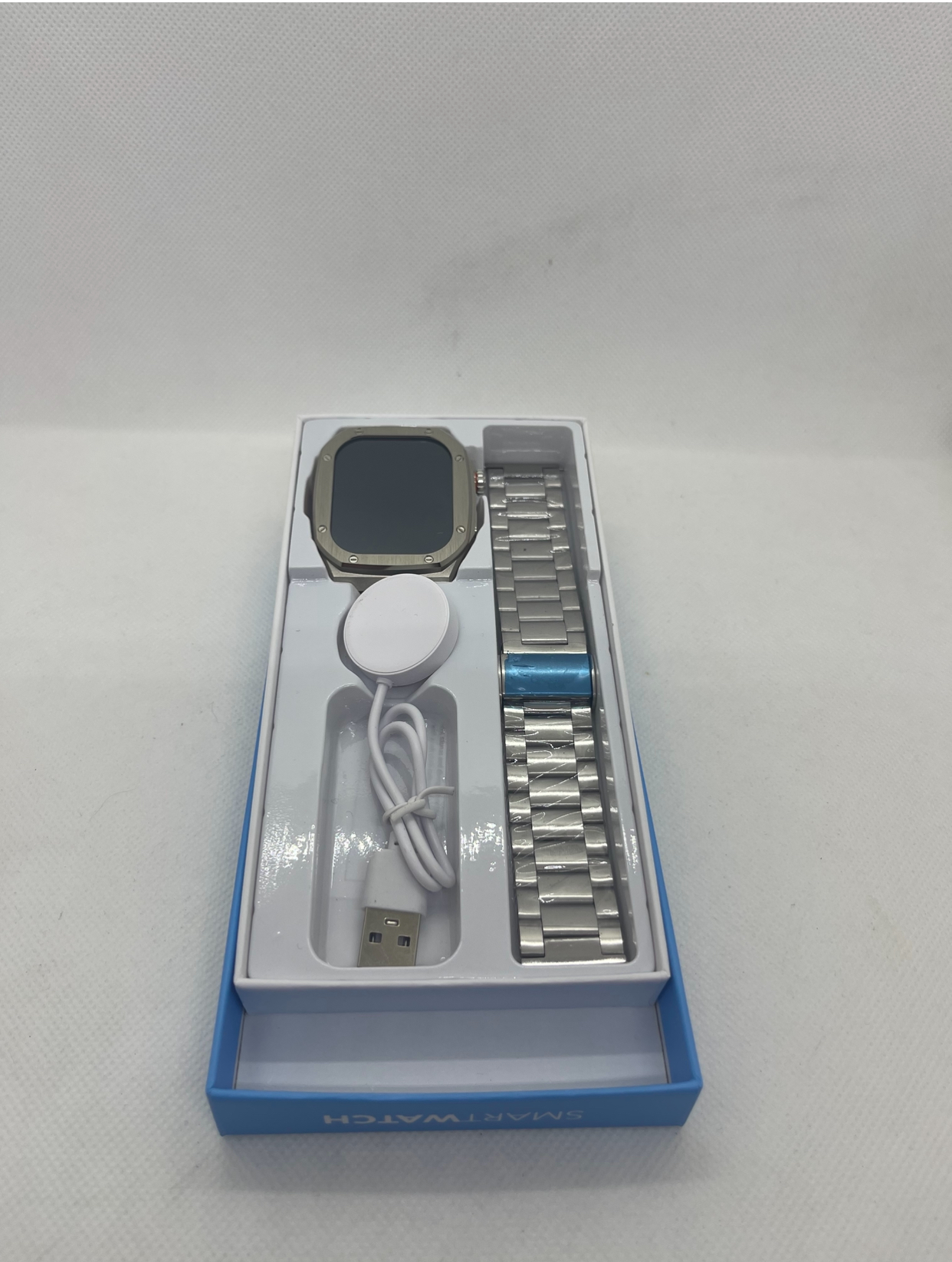 Smartwatch Z17 Max Smartwatch com bracelete metálica prateada e cabo USB branco em embalagem azul