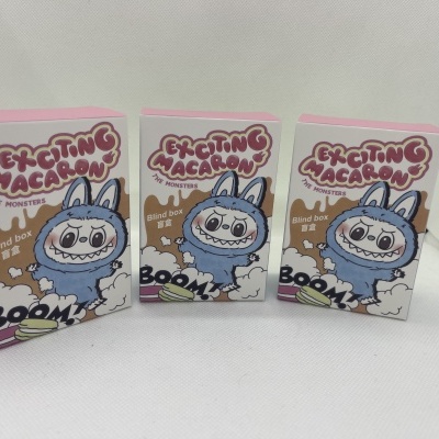 Três caixas de papel branco com ilustração de monstro azul e texto Exciting Macaron The Monsters