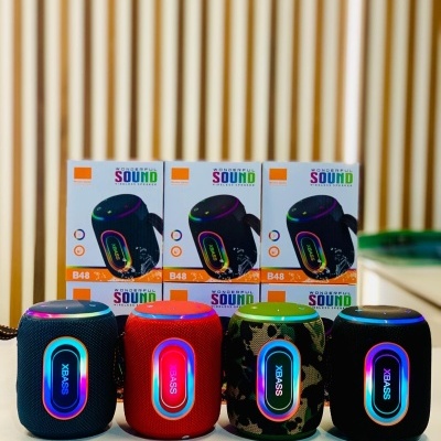 Quatro colunas de som portáteis coloridas com luzes LED e caixas com rótulo SOUND ao fundo