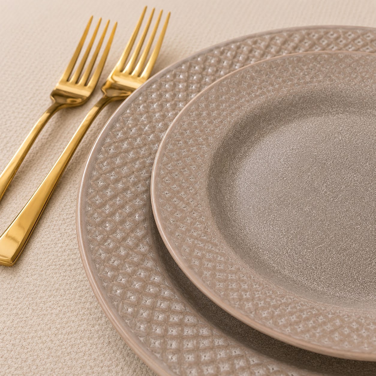 Conjunto de Louça de Mesa Bege Pérola em Grés Conjunto de loiça com dois pratos castanhos e dois garfos dourados sobre superfície bege
