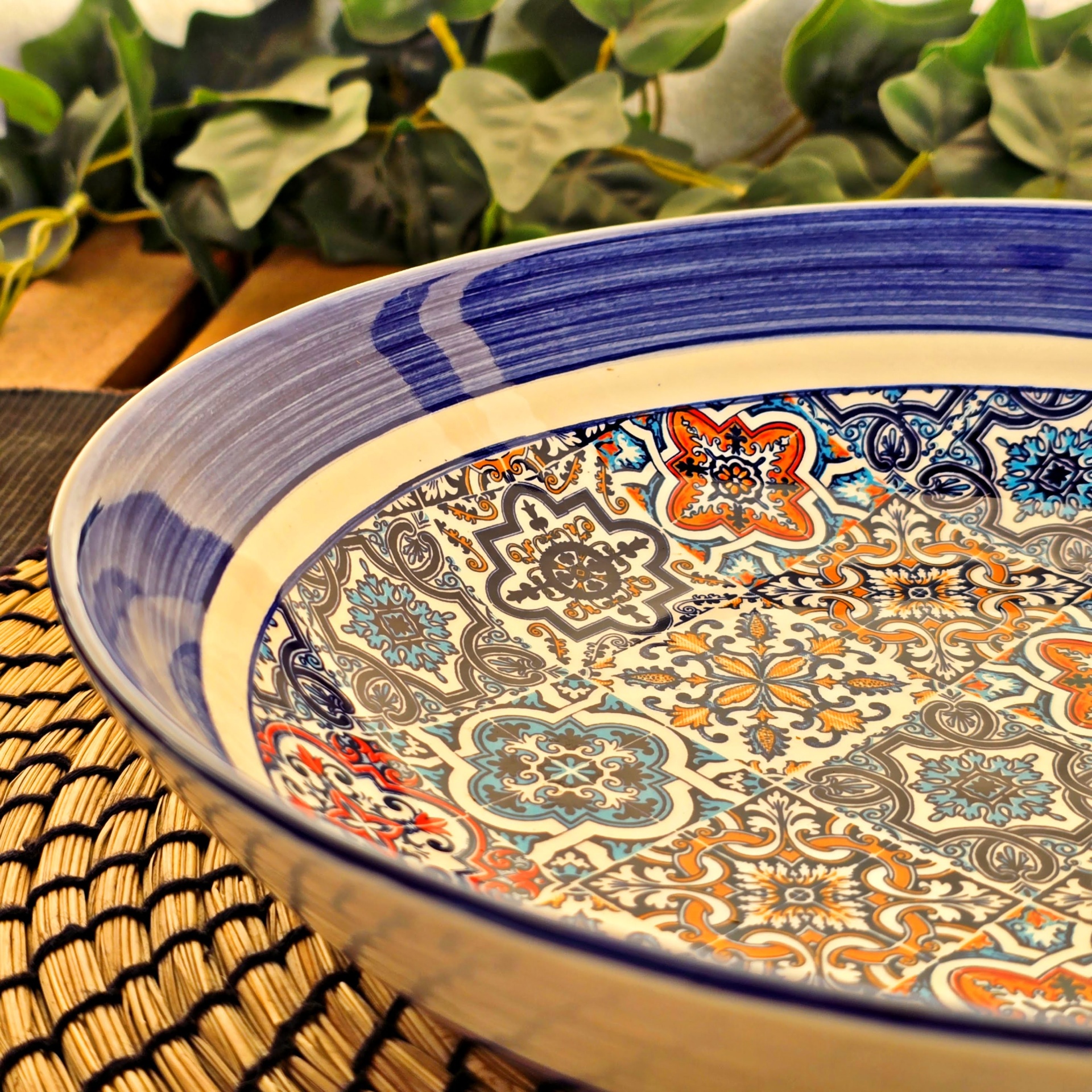 Saladeira / Fruteira Prato cerâmico decorado com padrões geométricos coloridos na borda azul em tecido trançado.
