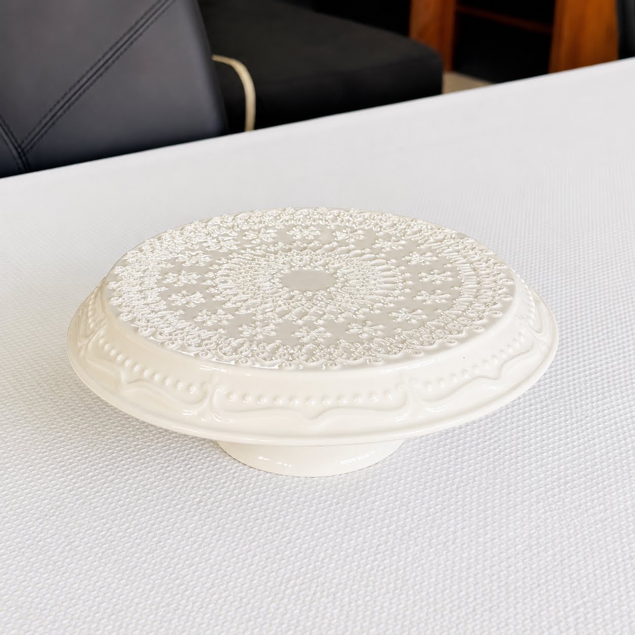 Coleção Grés Decorado Branco Prato branco em cerâmica com padrão floral em relevo numa mesa branca.