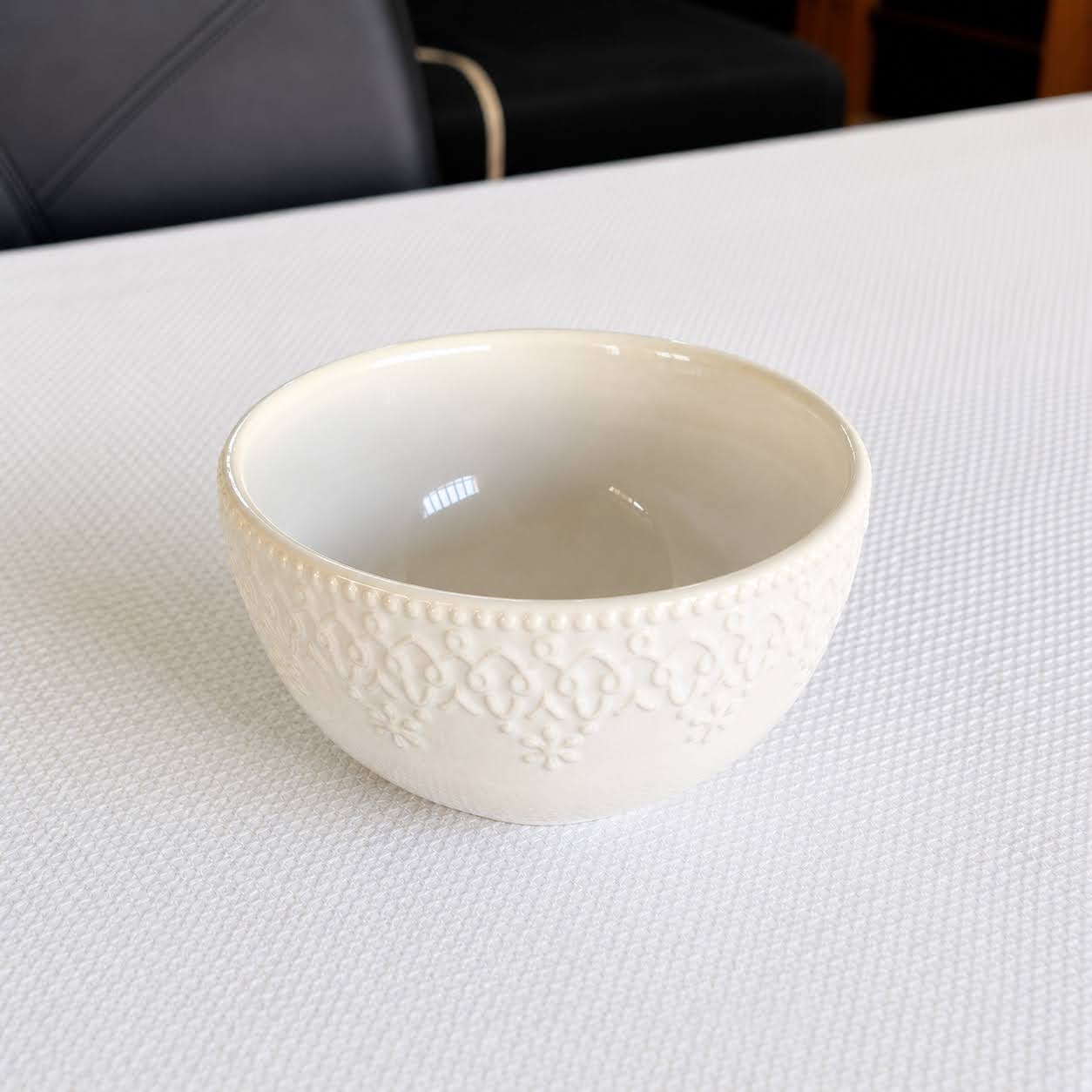 Coleção Grés Decorado Branco Tigela de cerâmica branca com padrão texturizado colocada sobre mesa branca