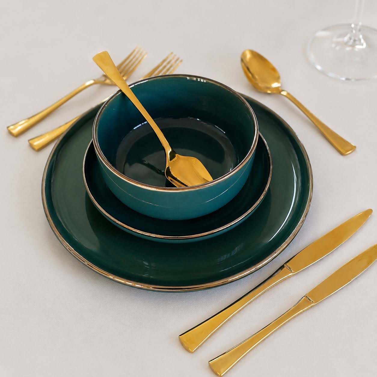 Conjunto de Mesa Verde Esmeralda | 3 Peças Conjunto de pratos e tigela azul escura com talheres dourados sobre superfície branca.