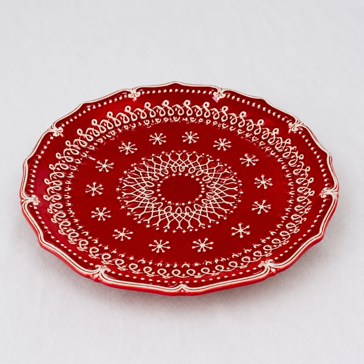 Coleção Grés Decorado Vermelho Prato cerâmico vermelho com padrão branco espiral e estrelas, borda ondulada