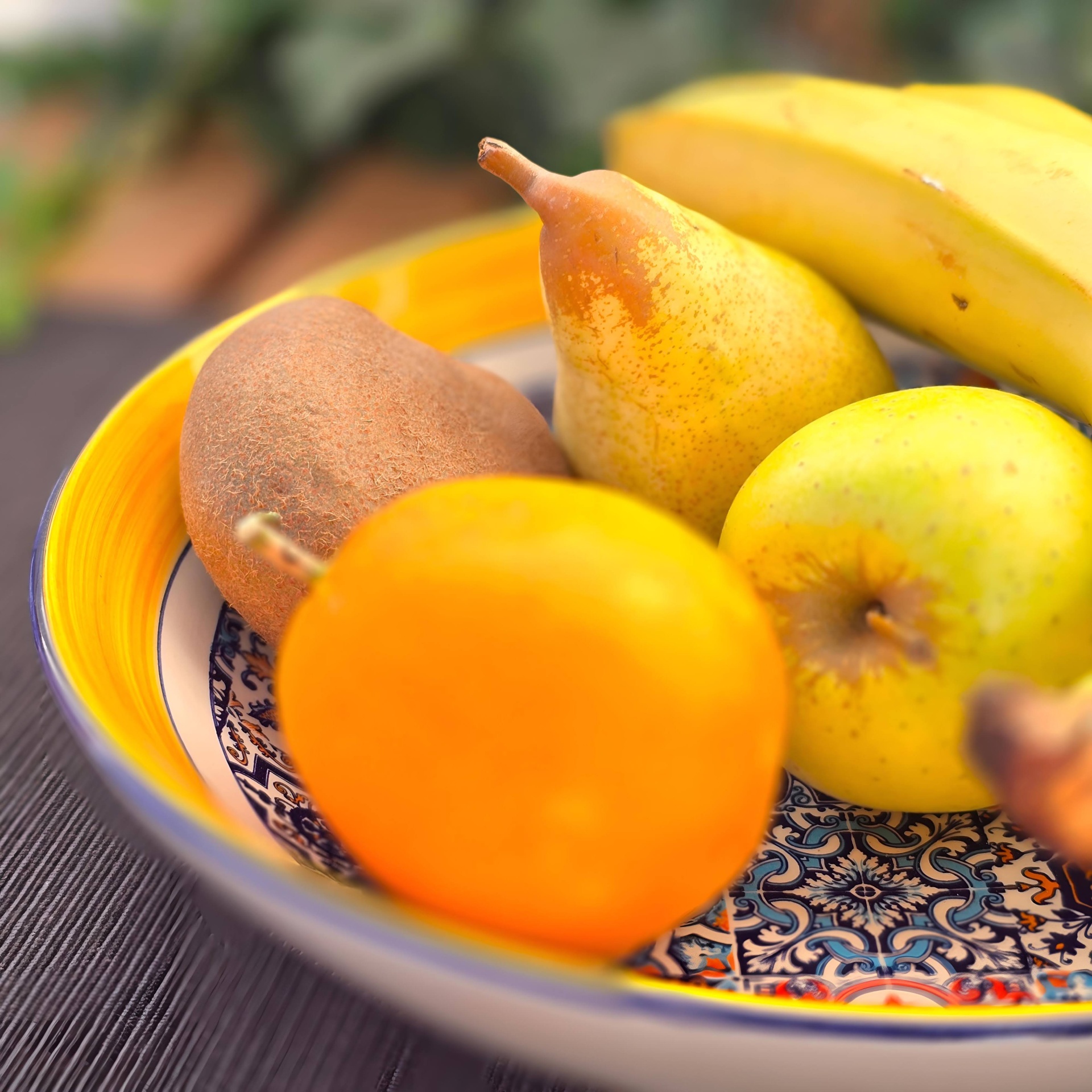 Saladeira / Fruteira Prato cerâmico decorativo com várias frutas, incluindo banana, pera, maçã verde, caqui e kiwi.