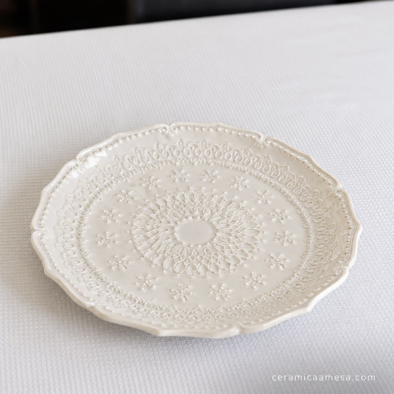 Coleção Grés Decorado Branco Prato branco decorativo em cerâmica com padrão em relevo sobre superfície branca