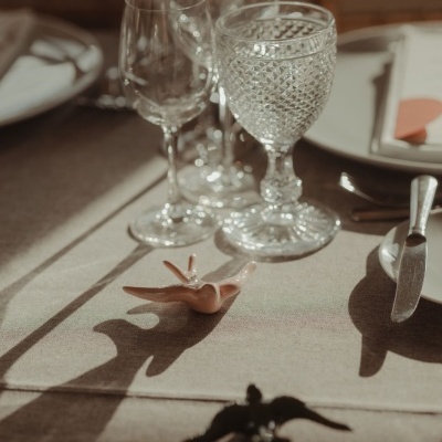 Copos de vidro transparente sobre mesa com toalha bege e talheres