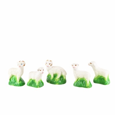 Cinco figuras de ovelhas brancas em cerâmica sobre bases verdes de relva.