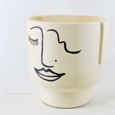 Vaso cerâmico branco com desenho de rosto estilizado em preto
