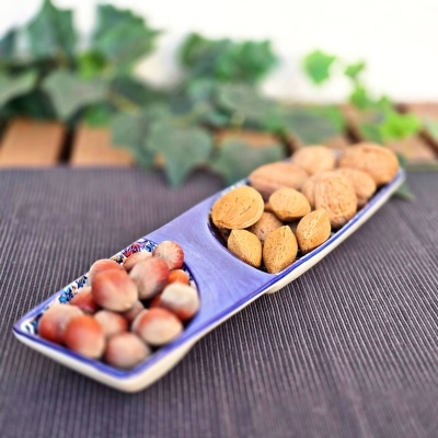 Tigela dupla com avelãs e amêndoas sobre tecido cinza