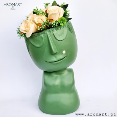 Vaso verde em forma de cabeça com flores artificiais creme e verdes