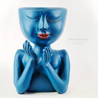 Vaso decorativo azul em forma de figura humana com lábios vermelhos e detalhes dourados.