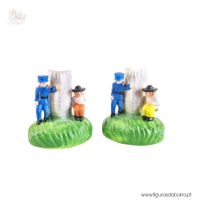 Par de figuras decorativas em cerâmica com crianças ao lado de árvores sobre base verde