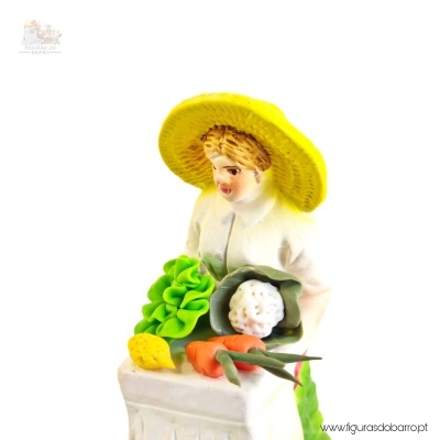 Estatueta em porcelana de mulher com chapéu amarelo e legumes coloridos
