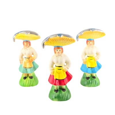 Figuras de brinquedo coloridas em forma de mulher com saia, avental amarelo e chapéu amarelo com detalhes prateados em base verde.