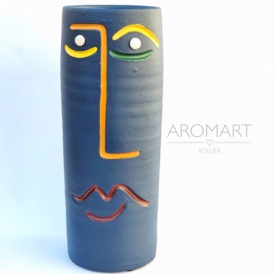 Vaso azul com rosto colorido e texto AROMART ATELIER