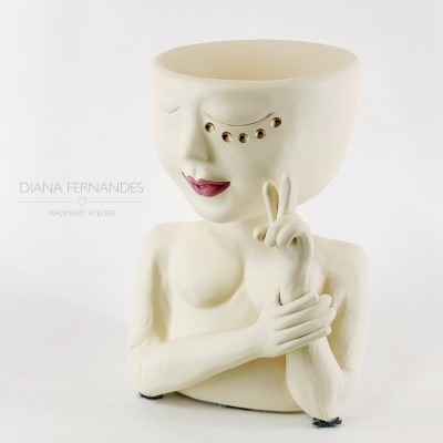 Vaso cerâmico em forma de busto humano com detalhes faciais dourados e expressão serena