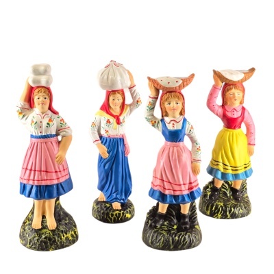 Quatro figuras de mulheres em cerâmica com roupas tradicionais e objetos na cabeça.