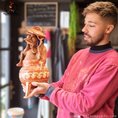 Homem com camisola rosa segura figura decorativa de cerâmica marrom com padrão branco