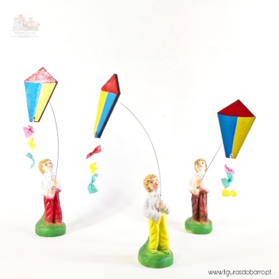 Três miniaturas de crianças com pipas coloridas em base branca