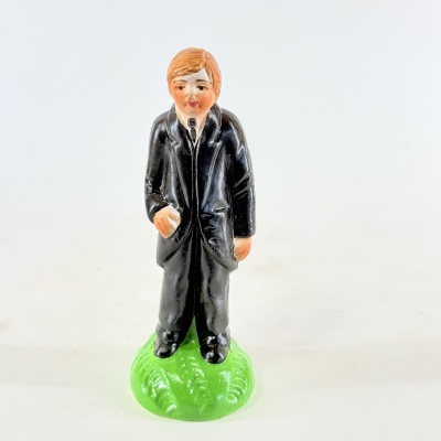 Figura de homem em fato preto sobre base verde