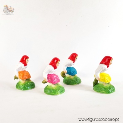 Figuras decorativas de cerâmica com mulheres de lenço vermelho e saia colorida sobre base verde