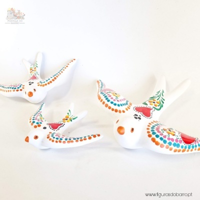 Figuras decorativas de pássaros brancos pintados com pontos coloridos e motivos florais